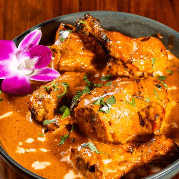 Mehfil Indian Restaurant's chicken tikka masala, garnished with cilantro and a purple orchid.