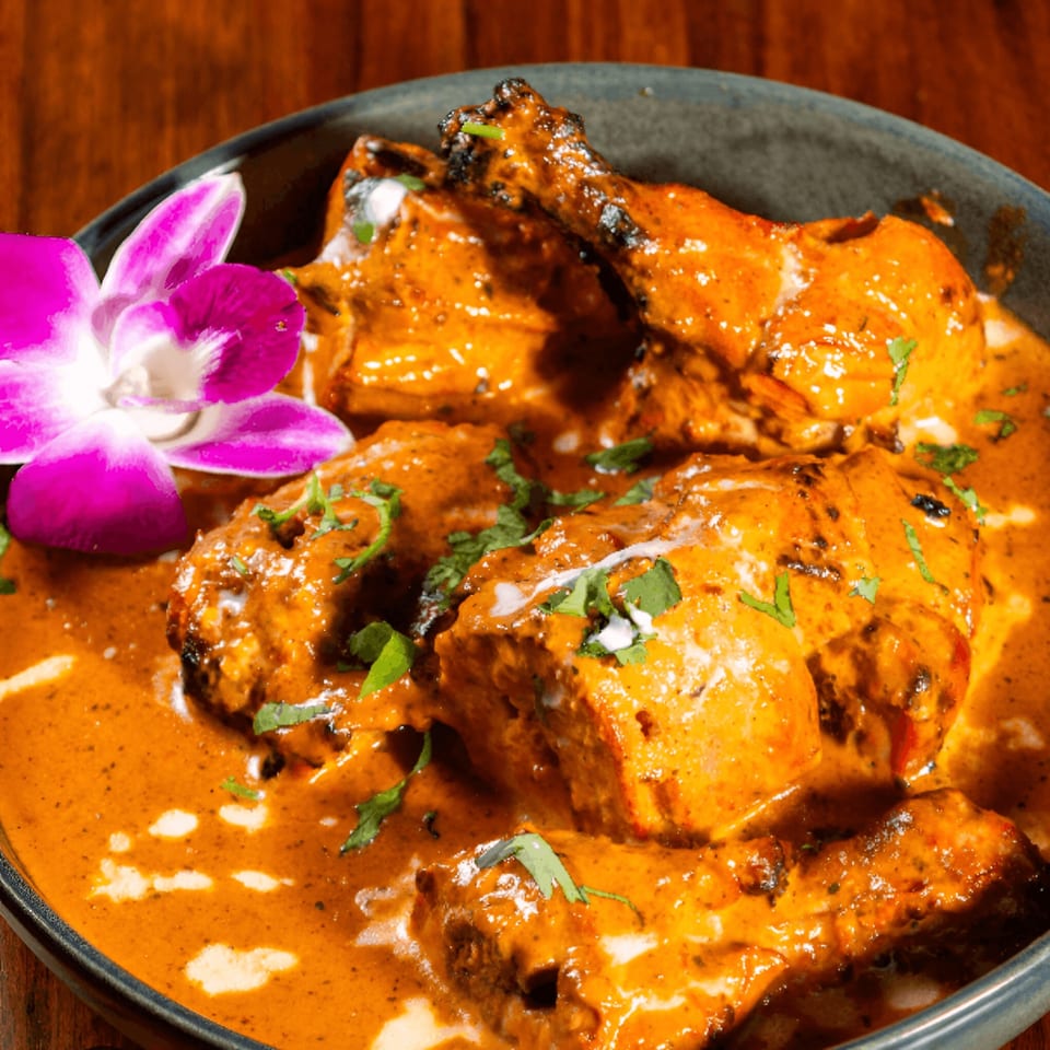 Mehfil Indian Restaurant's chicken tikka masala, garnished with cilantro and a purple orchid.
