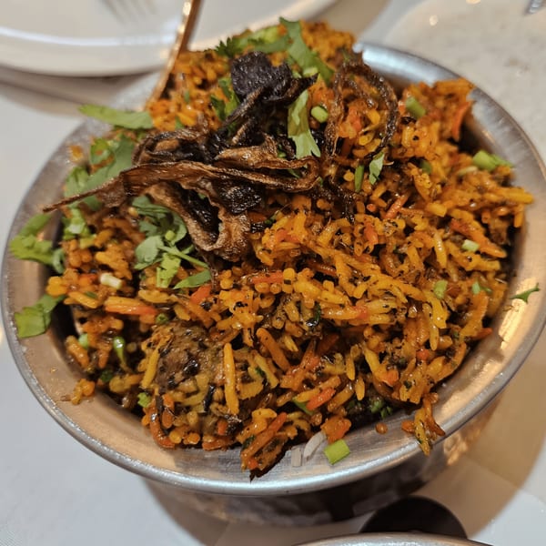 Close-up of Mehfil Indian Restaurant's biryani, garnished with fried onions and fresh cilantro.