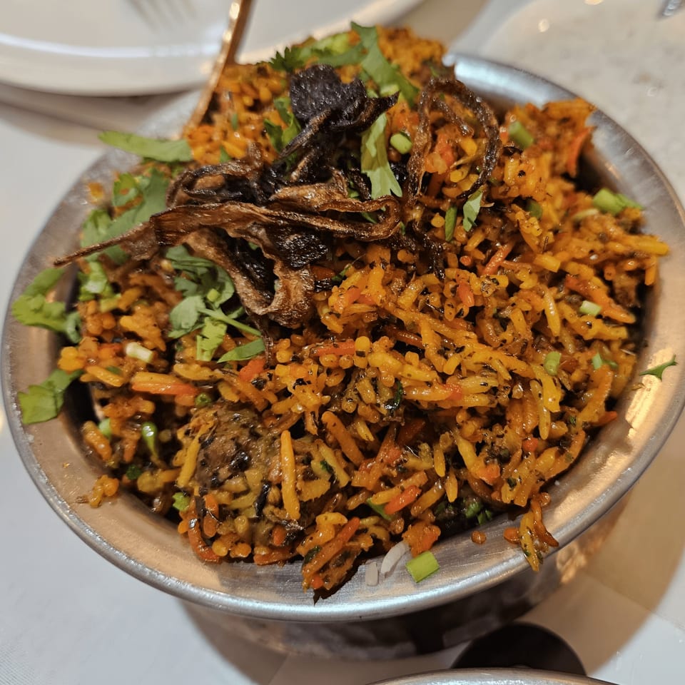 Close-up of Mehfil Indian Restaurant's biryani, garnished with fried onions and fresh cilantro.