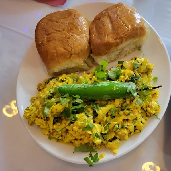 Indian scrambled paneer with green chili and cilantro, served with two fluffy buns.